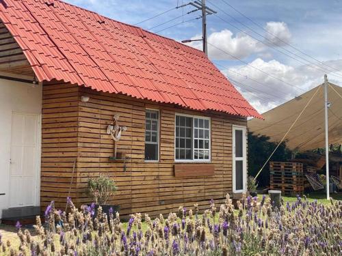 a wooden house with an orange roof with purple flowers at Cabaña BC Amecameca in Amecameca de Juárez