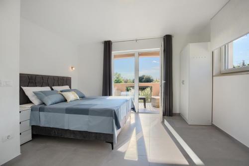 a white bedroom with a bed and a balcony at Villa Harmony - Apartments in Banjole