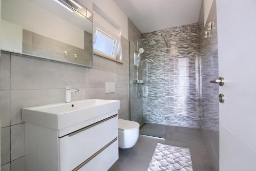 a bathroom with a sink and a toilet and a shower at Villa Harmony - Apartments in Banjole