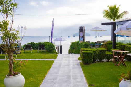 a walkway through a resort with the beach in the background at Hotel Sete Ilhas in Florianópolis