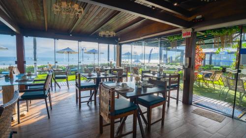 a restaurant with tables and chairs and a view of the ocean at Hotel Sete Ilhas in Florianópolis