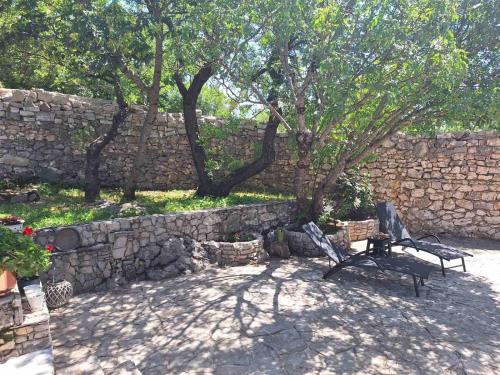 a stone wall with a bench next to a tree at Vila Agroturizam Kućica Mostar-Welcome bikers in Mostar