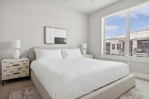 a white bedroom with a large bed and a window at Kasa Noda Charlotte in Charlotte