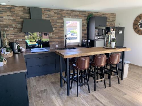une cuisine avec un grand comptoir en bois avec des tabourets dans l'établissement Maison au calme avec piscine chauffée à 10 mn des plages, à Seignosse