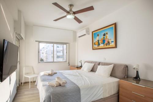 a white bedroom with a bed and a ceiling fan at Neapolis Residence Spacious Quiet Near beach in Limassol