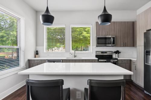 a kitchen with a white island and black chairs at Kasa Noda Charlotte in Charlotte