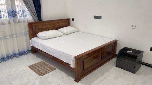 a bedroom with a wooden bed with white sheets at The Apex House in Torayaya