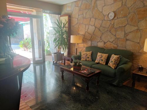 a living room with a green couch and a stone wall at Hotel Suite Mioño Castro Urdiales in Castro-Urdiales