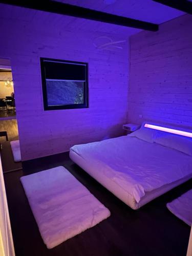 a purple room with two beds and a brick wall at Cabanele din Valea Ursului in Bîrsana