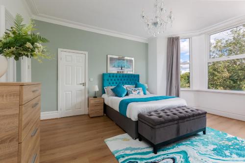 a bedroom with a large bed and a blue headboard at Grand Victorian Villa 6 - En-Suites, Hot Tub, Cinema Room, Private Parking & Park View in Liverpool