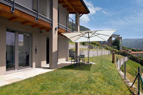 a patio with a table and an umbrella next to a building at Appartamenti Caffè Maya in Maslianico