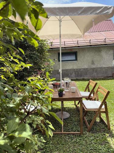 a wooden table with two chairs and an umbrella at Kuća za odmor PEPA in Brod Moravice