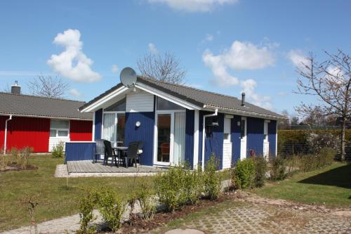 a blue and white house with a chair on a porch at Strandpark 13 in Grömitz