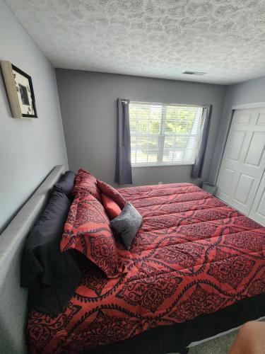a bedroom with a bed with a red blanket and a window at FC Suites in Cincinnati
