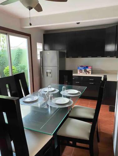 a kitchen with a glass table with chairs and a refrigerator at Alojamiento La buena estancia! in Santa Cruz de las Flores