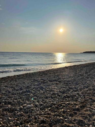 a beach with the sun rising over the ocean at Villa Georgia in Kastrosikia