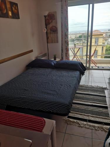 un lit dans une chambre avec une grande fenêtre dans l'établissement Le Mariline, à Nice