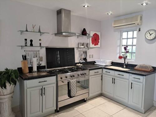 a kitchen with white cabinets and a stove top oven at Beautiful villa less than 5 minutes from the beach in Jolly Harbour