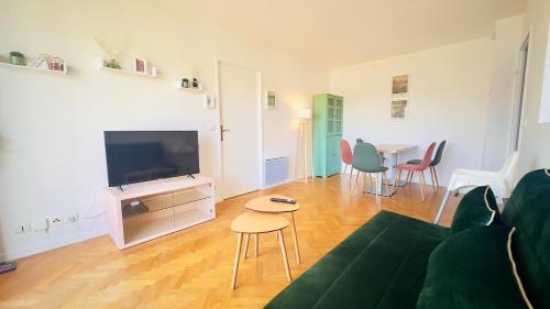 een woonkamer met een bank, een tv en een tafel bij Le Jardin Suspendu, Steps to Lake & Station in Bussy-Saint-Georges
