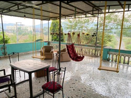 a patio with a table and chairs and hammocks at Sukh Villas - Best Budget villa in Karjat in Karjat