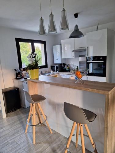 a kitchen with a counter and two stools at Foyer pagrita in Bretteville-sur-Odon