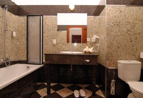 a bathroom with a sink and a tub and a toilet at Golf Resort Hotel Konopiště in Benešov