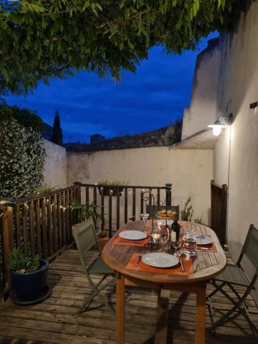 - une table et des chaises en bois sur une terrasse la nuit dans l'établissement Maison de charme, à Caunes-Minervois