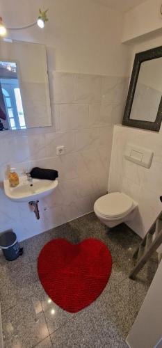 a bathroom with a red heart rug on the floor at Am alten Deich in Sande