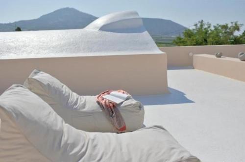 a person sitting on a bench with their feet on a roof at Wonderful Santorini Villa Alia Mansion 3 Bedrooms Beautiful Outdoor Space & Wonderful Views Megalochori in Megalokhori