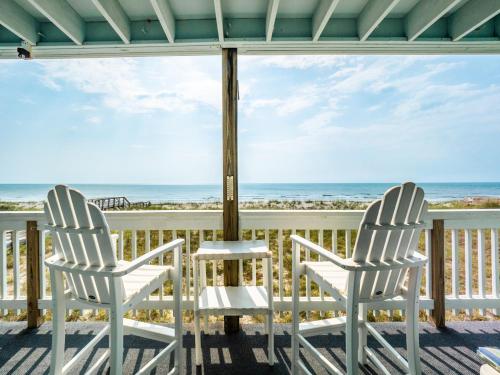 two white chairs sitting on a porch overlooking the ocean at Sands III #2B - A BluSea in Carolina Beach