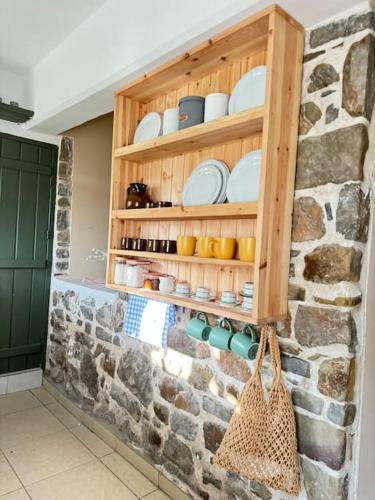 a kitchen with a stone wall with shelves and dishes at Traditional maisonette just 15' from Kalamata in Valíra