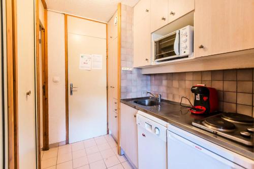 une petite cuisine avec un évier et un micro-ondes dans l'établissement Résidence LES COTES - Studio pour 3 Personnes MAE-9594, à Aime La Plagne
