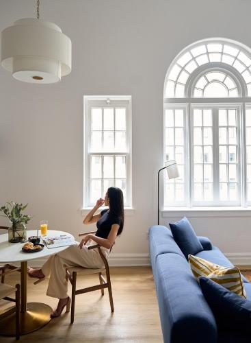 a woman sitting on a chair in a living room at Rusk House Serviced Apartments in Houston