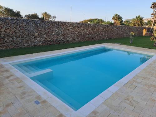 a large blue swimming pool in front of a stone wall at Villa Albamonte in Carini