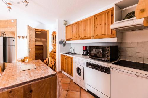 une cuisine avec des appareils électroménagers blancs et des armoires en bois dans l'établissement Résidence LE TETRAS LYRE - 2 Pièces pour 6 Personnes MAE-0134, à Aime La Plagne