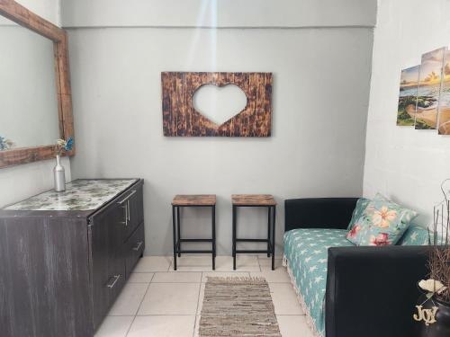 Una sala de estar con un sofá y un cuadro de corazón en la pared. en Beauty Max, en Hermanus