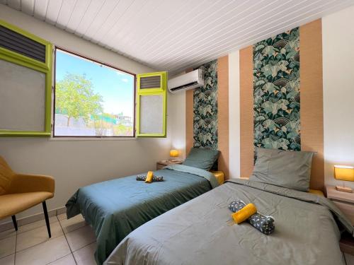 a room with two beds and a window at Casa François - Terrasse vue mer & clim in Le Carbet
