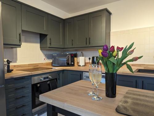 a kitchen with a table with a vase of purple tulips at Two Bedroom Duplex Apartment in Swansea