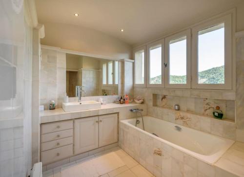 une grande salle de bain avec une baignoire et un lavabo dans l'établissement Villa FrancaRoc - Vue mer au coeur des rochers, à Grimaud