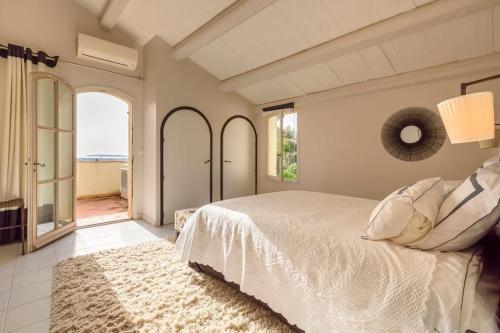 une chambre avec un lit blanc et une grande fenêtre dans l'établissement Villa FrancaRoc - Vue mer au coeur des rochers, à Grimaud