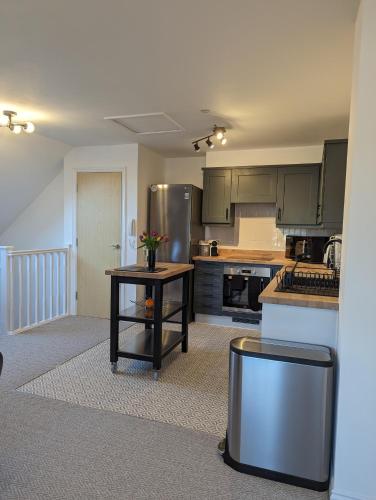 a kitchen with stainless steel appliances and a table at Two Bedroom Duplex Apartment in Swansea