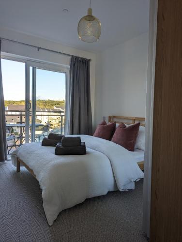 a bedroom with a large white bed with a balcony at Two Bedroom Duplex Apartment in Swansea