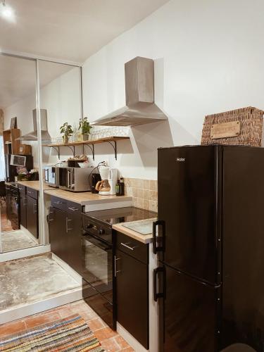 une cuisine avec un réfrigérateur noir et une cuisinière dans l'établissement La petite Maison Rouge, à Portel-des-Corbières