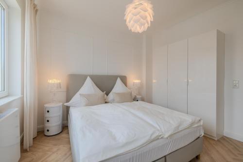a bedroom with a bed with white sheets and a chandelier at Hanse Villa - Apartment Lübeck in Lübeck