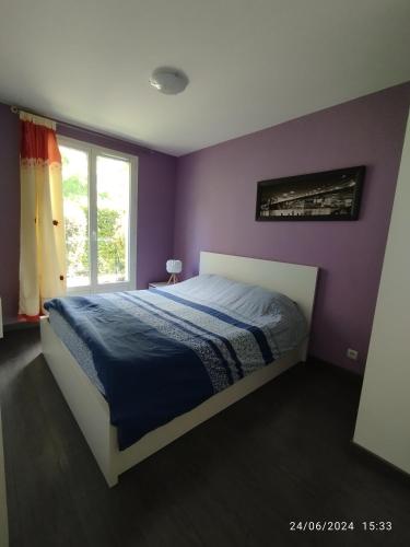 a bedroom with a bed with purple walls and a window at appartement proche de Disney et val d Europe in Chessy