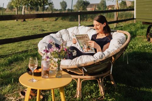 Una donna seduta su una sedia a leggere un libro di Tiny House De Skure a Harelbeke