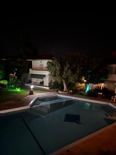 a swimming pool at night with a building in the background at Palm trees apartment in Pefkohori