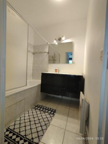 une salle de bain avec une baignoire, un lavabo et un miroir dans l'établissement appartement proche de Disney et val d Europe, à Chessy