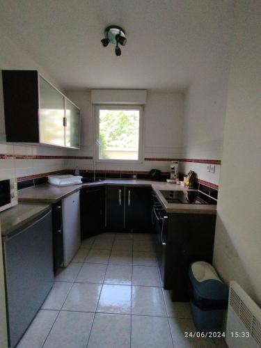 une petite cuisine avec un évier et une fenêtre dans l'établissement appartement proche de Disney et val d Europe, à Chessy