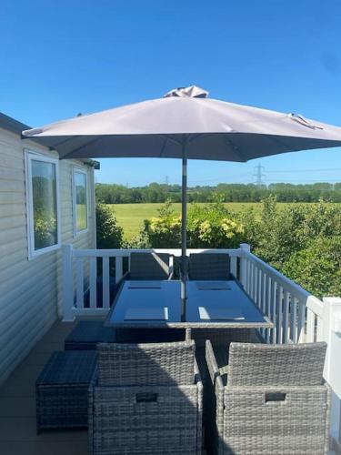 a patio with an umbrella and chairs on a porch at Holiday home in Furzehill in Wimborne Minster